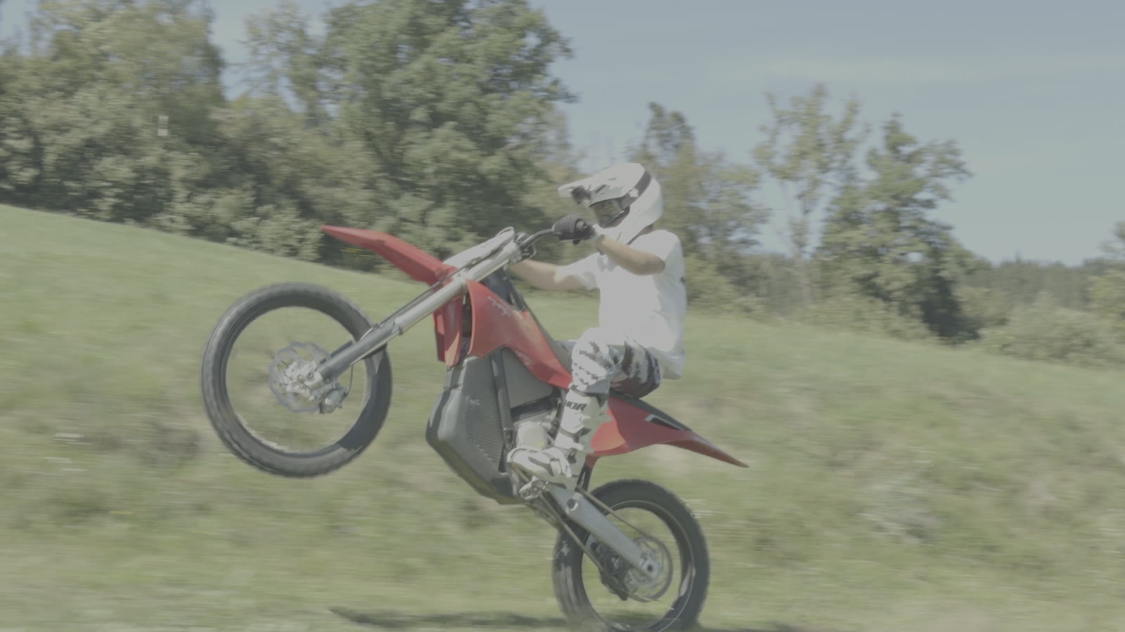Motorrad-Fahrer im Wheelie auf einer Wiese, unbearbeitetes Log-Material